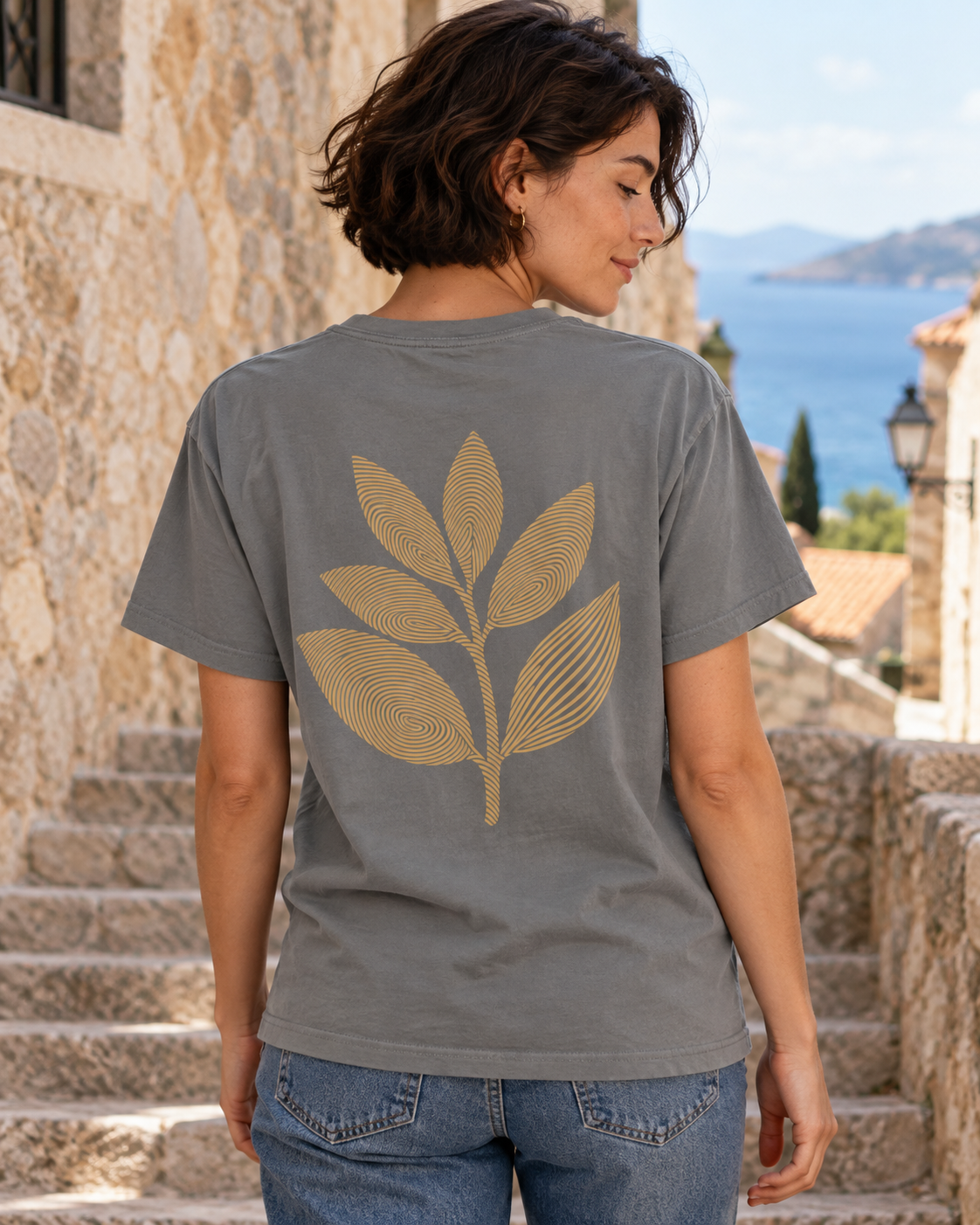 AI lifestyle mockup: grey Imprint T-shirt worn from the back, showing the gold fingerprint leaf artwork.